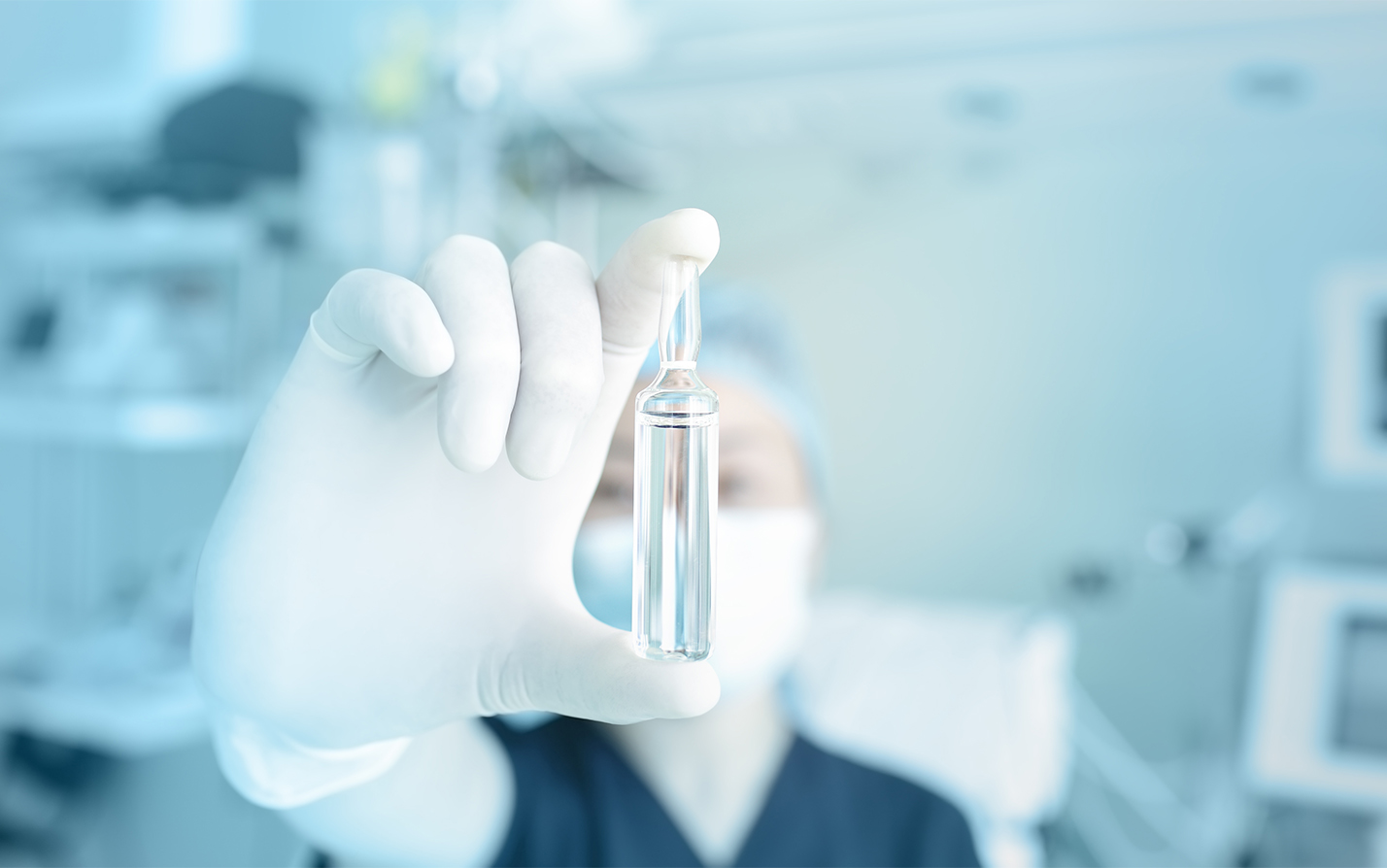 Scientist in background holding filled vial in foreground